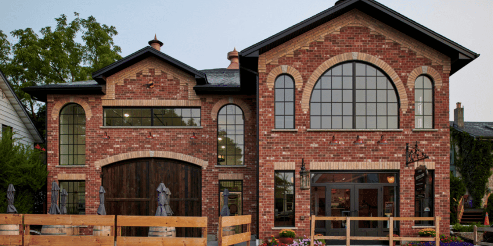 Black framed windows and doors on the Elora Distilling Company. Red brick building with black framed windows and doors looking from across the street.