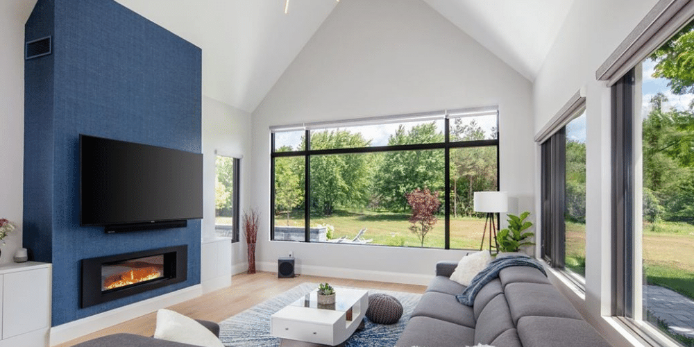 Living room with black window frames looking out to the backyard and a blue feature fireplace.